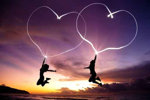 young couple jumping and drawing connected hearts by flashlight